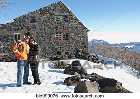 Stock Photograph - Hispanic couple standing in snow near house. Fotosearch