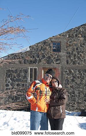 Stock Photography - Hispanic couple standing in snow near house. Fotosearch