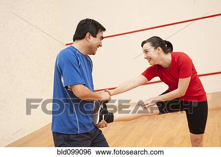 Stock Photograph - Hispanic couple stretching before racquetball. Fotosearch
