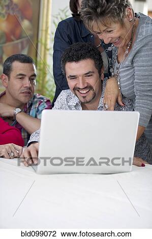 Stock Image - Hispanic family looking at laptop. Fotosearch
