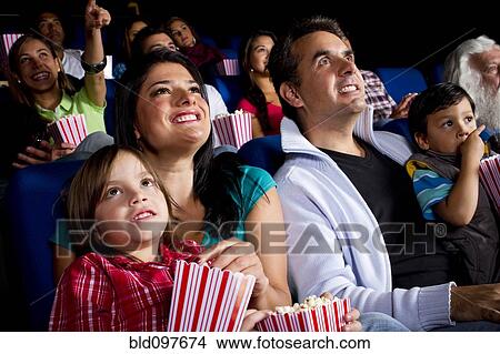 Picture - Hispanic family watching film in movie theater. Fotosearch
