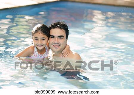 Stock Photo - Hispanic father and daughter swimming in pool. Fotosearch