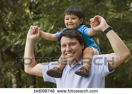Stock Photo - Hispanic father carrying son on shoulders. Fotosearch