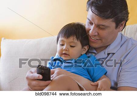 Picture - Hispanic father showing cell phone to his son. Fotosearch