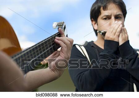 Hispanic friends playing guitar and harmonica View Large Photo Image Stock Photo - Hispanic friends playing guitar and harmonica. Fotosearch