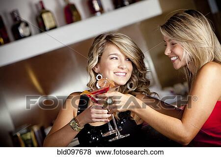 Stock Photo - Hispanic friends toasting with martinis. Fotosearch