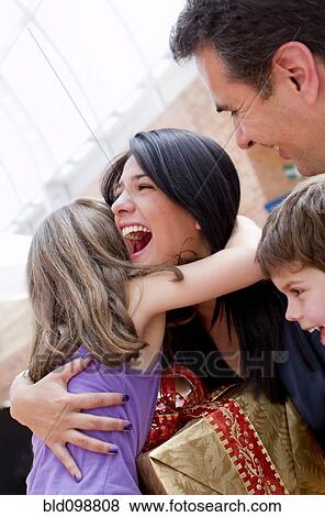 Stock Photo - Hispanic girl giving excited mother birthday gift. Fotosearch