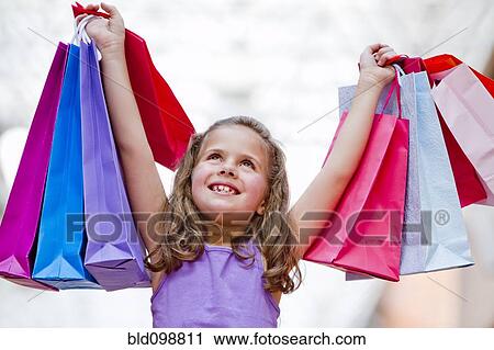 Stock Image - Hispanic girl lifting shopping bags. Fotosearch