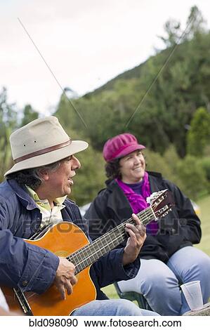 Stock Image - Hispanic man playing guitar for friends. Fotosearch