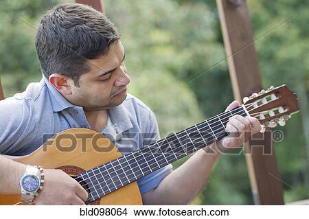 Picture - Hispanic man playing guitar. Fotosearch