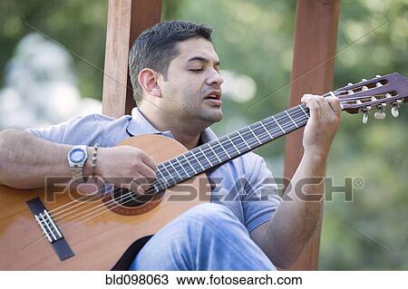 Stock Image - Hispanic man playing guitar. Fotosearch