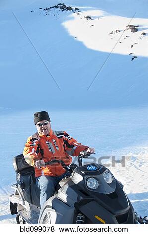 Stock Photo - Hispanic man riding on snowmobile. Fotosearch