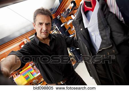 Stock Photography - Hispanic man shopping for clothes in store. Fotosearch