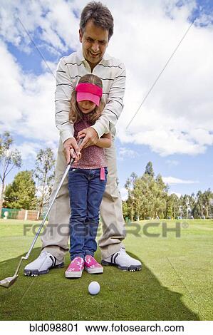 Stock Image - Hispanic man teaching girl to play golf. Fotosearch