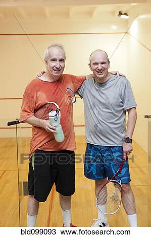 Stock Image - Hispanic men relaxing after racquetball. Fotosearch