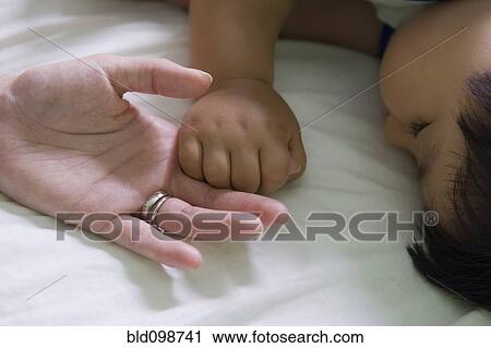 Stock Image - Hispanic mother and baby boy holding hands. Fotosearch