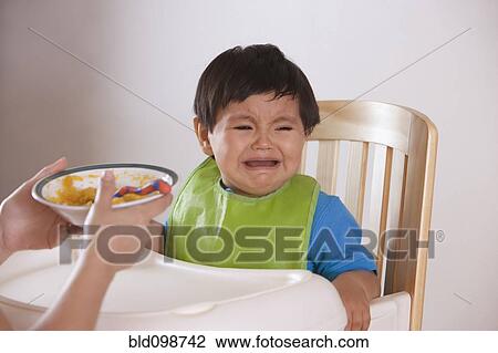 Hispanic mother trying to feed crying baby boy View Large Photo Image Stock Image - Hispanic mother trying to feed crying baby boy. Fotosearch