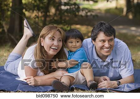 Stock Image - Hispanic parents enjoying park together. Fotosearch