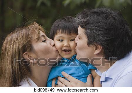 Stock Photo - Hispanic parents kissing baby boy. Fotosearch