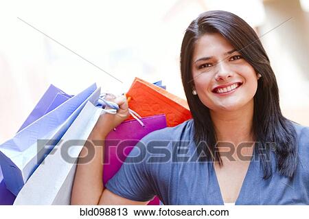 Stock Image - Hispanic woman carrying shopping bags. Fotosearch