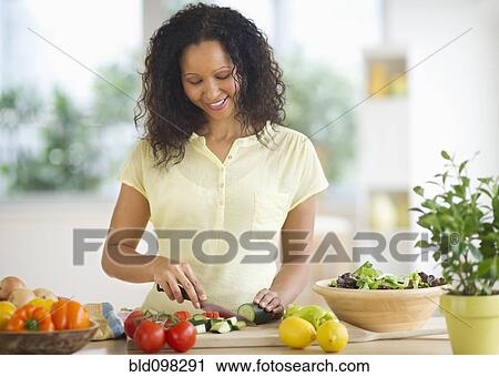 Stock Image - Hispanic woman chopping vegetables. Fotosearch