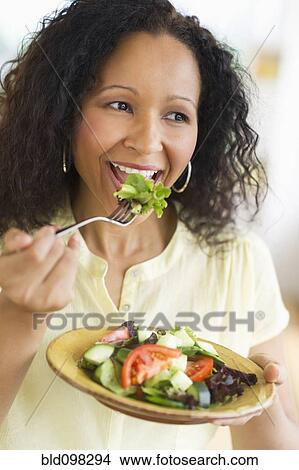 Picture - Hispanic woman eating salad. Fotosearch