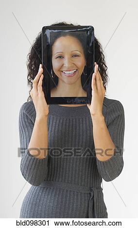 Stock Image - Hispanic woman holding digital tablet in front of face. Fotosearch