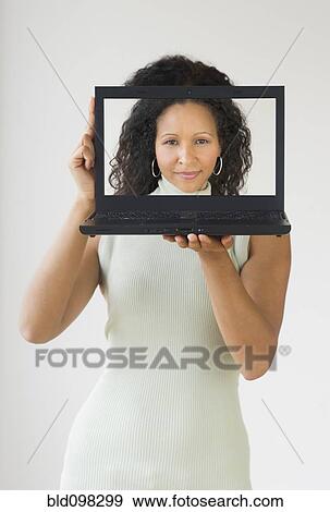 Stock Photo - Hispanic woman holding laptop in front of her face. Fotosearch