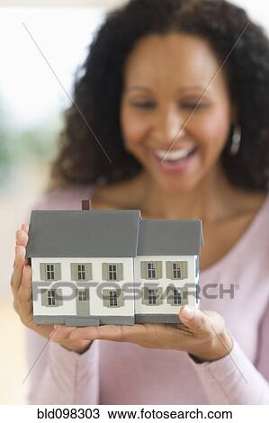 Stock Image - Hispanic woman holding miniature house. Fotosearch