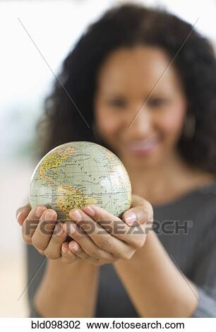 Stock Image - Hispanic woman holding small globe. Fotosearch