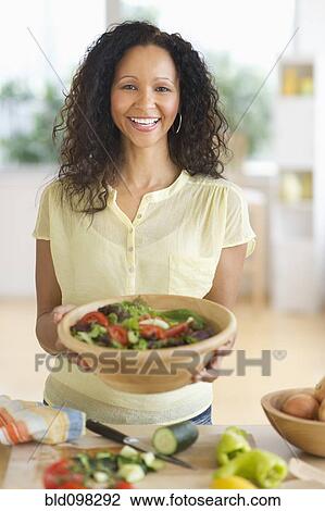 Stock Image - Hispanic woman preparing salad. Fotosearch