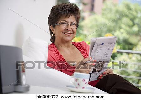 Stock Image - Hispanic woman reading newspaper. Fotosearch