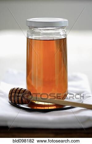 Stock Image - Honey in jar with dripper. Fotosearch