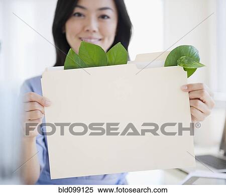 Stock Photography - Japanese businesswoman holding folder containing leaves. Fotosearch