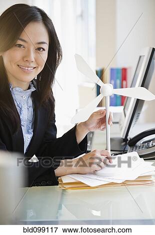 Stock Photo - Japanese businesswoman holding model wind turbine. Fotosearch