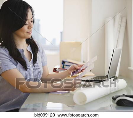 Stock Image - Japanese woman looking at paint swatches. Fotosearch
