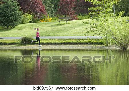 Jogger running near park pond View Large Photo Image Stock Photo - Jogger running near park pond. Fotosearch