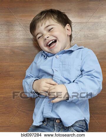 Picture - Laughing Caucasian boy laying on floor. Fotosearch
