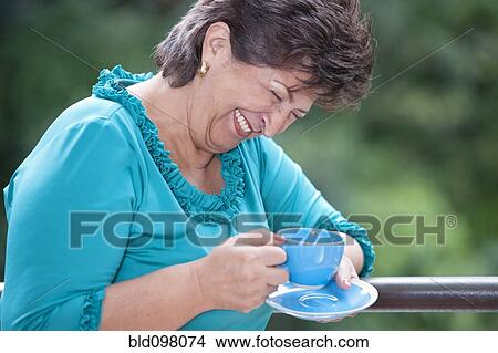Picture - Laughing Hispanic woman drinking coffee. Fotosearch