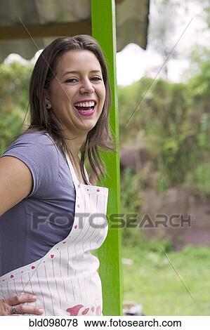Stock Photo - Laughing Hispanic woman wearing apron. Fotosearch