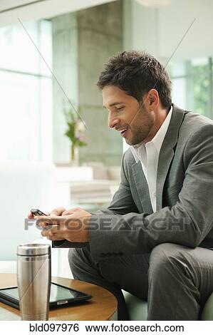 Stock Photograph - Mixed race businessman text messaging on cell phone. Fotosearch