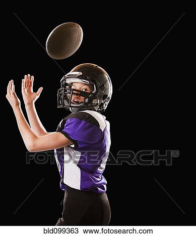 Stock Image - Mixed race football player catching football. Fotosearch