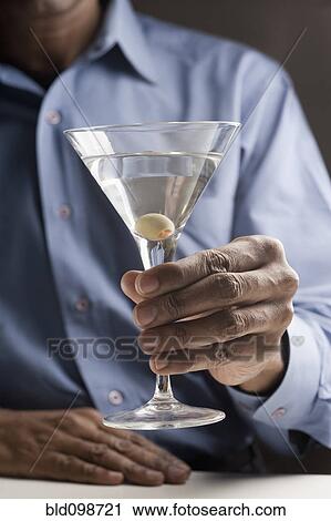 Stock Image - Mixed race man drinking martini. Fotosearch