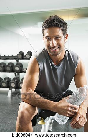 Mixed race man drinking water in gym View Large Photo Image Stock Photo - Mixed race man drinking water in gym. Fotosearch