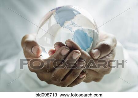 Stock Image - Mixed race man holding glass globe. Fotosearch