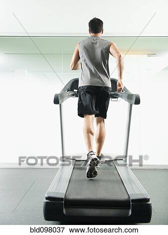 Stock Photo - Mixed race man running on treadmill. Fotosearch
