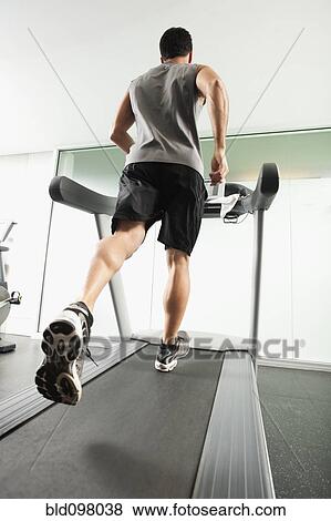 Stock Photo - Mixed race man running on treadmill. Fotosearch