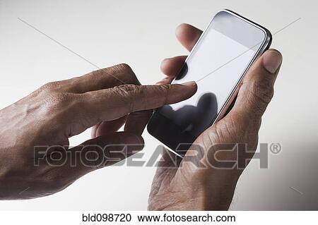 Stock Image - Mixed race man text messaging on cell phone. Fotosearch