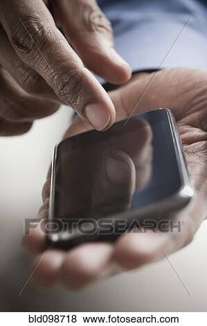 Stock Photo - Mixed race man text messaging on cell phone. Fotosearch