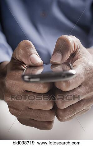 Stock Photo - Mixed race man text messaging on cell phone. Fotosearch